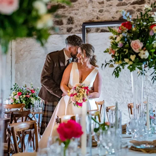 Bride and groom in Kinclune Steading wedding barn with luxury table settings and flowers. Wedding dress by The Hitching Post Bridal