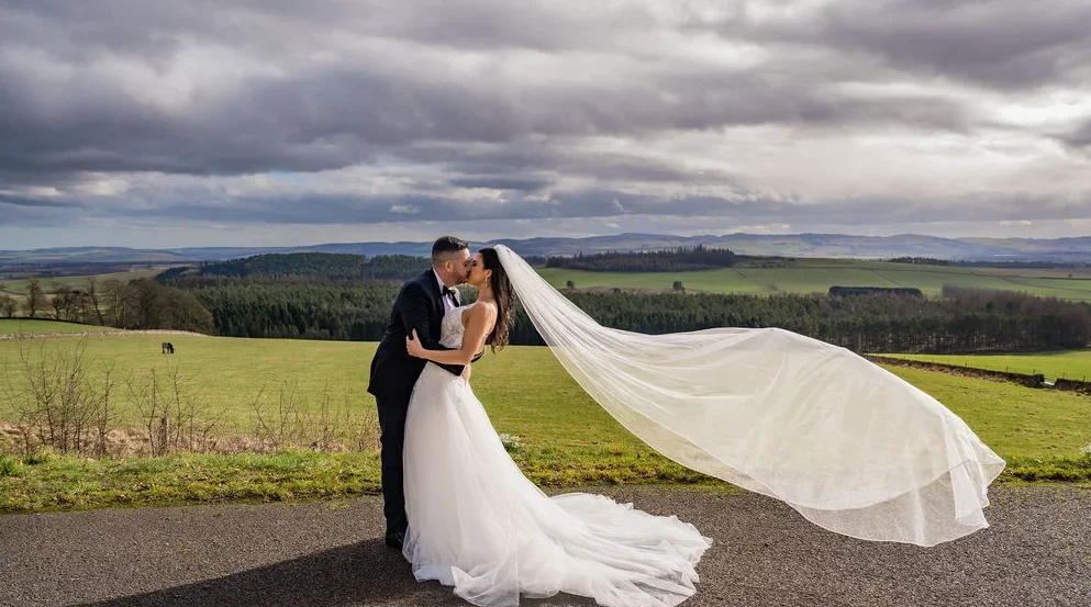 Bride and groom on the Kinclune House driveway with sweeping Angus countryside views. Dress by The Hitching Post Bridal. ZibiZPhoto