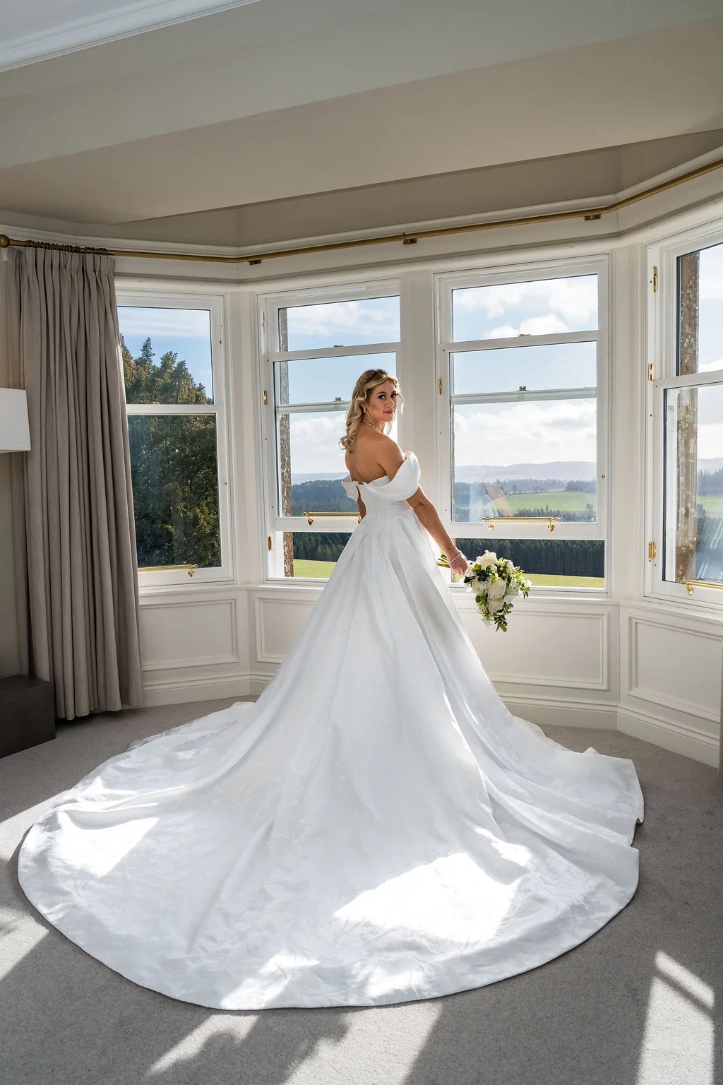Bride in the feature bay window of Kinclune House Bridal Suite with panoramic views. Dress by The Hitching Post Bridal. Photography by ZibiZPhoto.