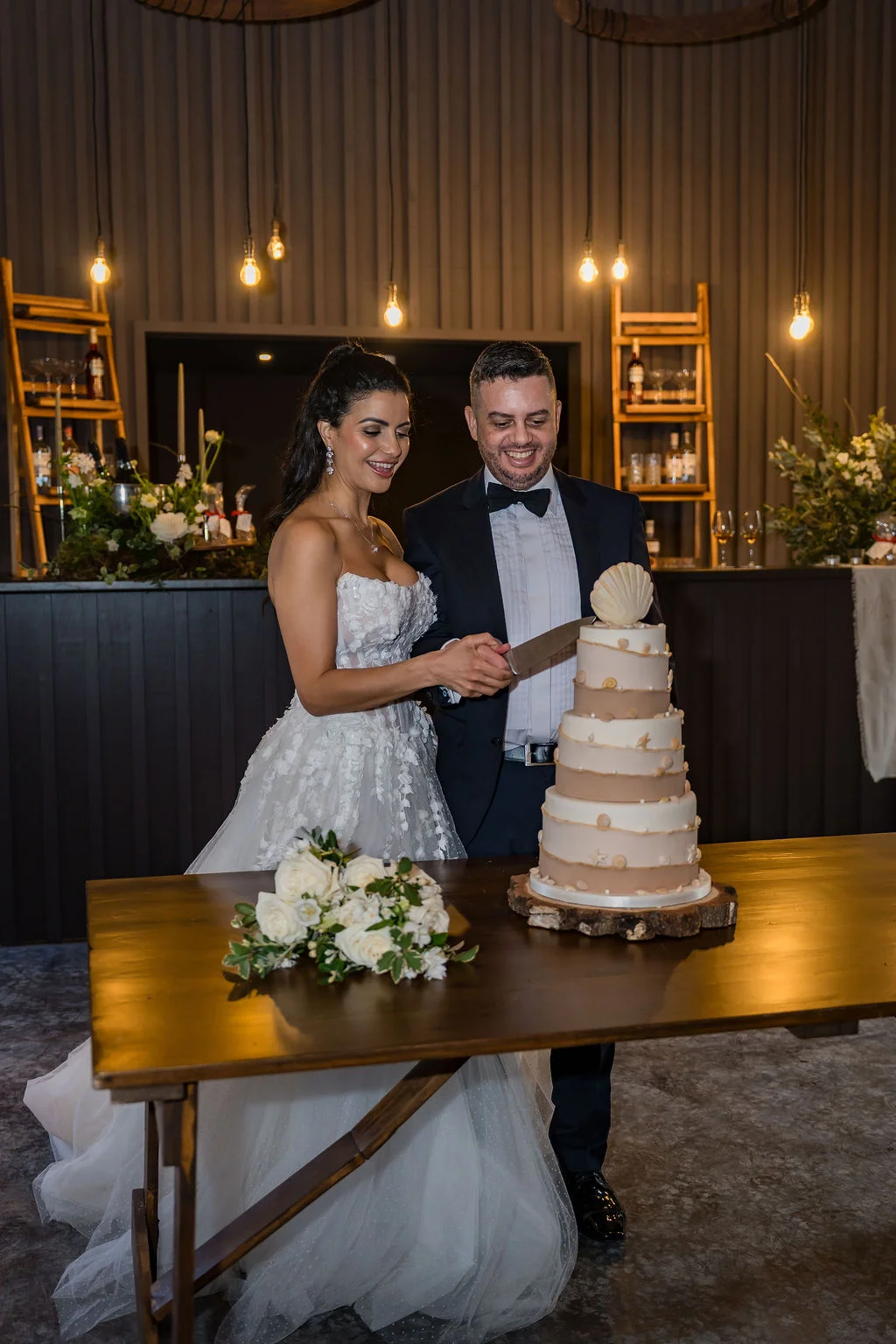 Cutting the wedding cake at Kinclune Steading Party Barn. Cake by JM Bakery. Dress by The Hitching Post bridal. ZibiZPhoto