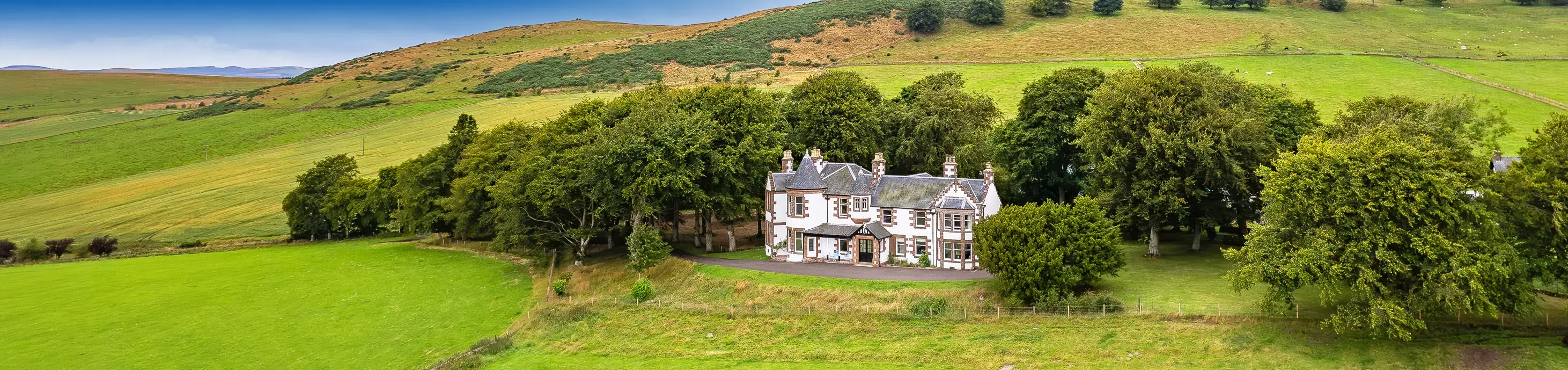 Kinclune House and Estate in summer with woodland, fields and rolling hills in Angus