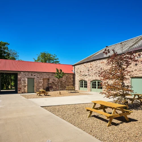 Kinclune Steading Victorian courtyard with picnic benches, fire pits and festoon lighting.